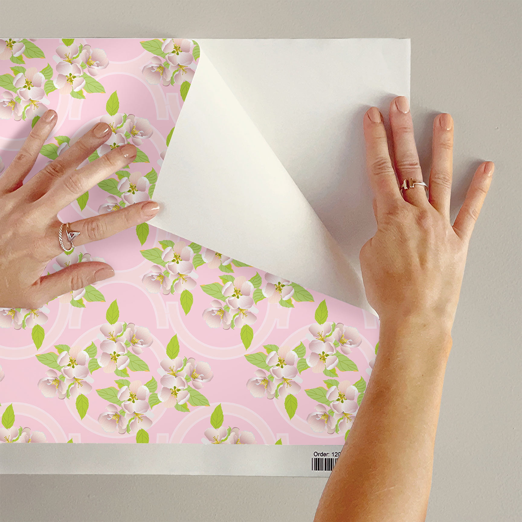 The artwork is a floral pattern showcasing delicate white and light pink blossoms with yellow stamens, complemented by vibrant green leaves. The flowers and leaves are distributed evenly across a soft pink background, which features subtle, pale geometric shapes that add depth without overpowering the organic floral elements.  The composition blends a gentle pastel color scheme with natural motifs, creating a light, fresh, and elegant aesthetic