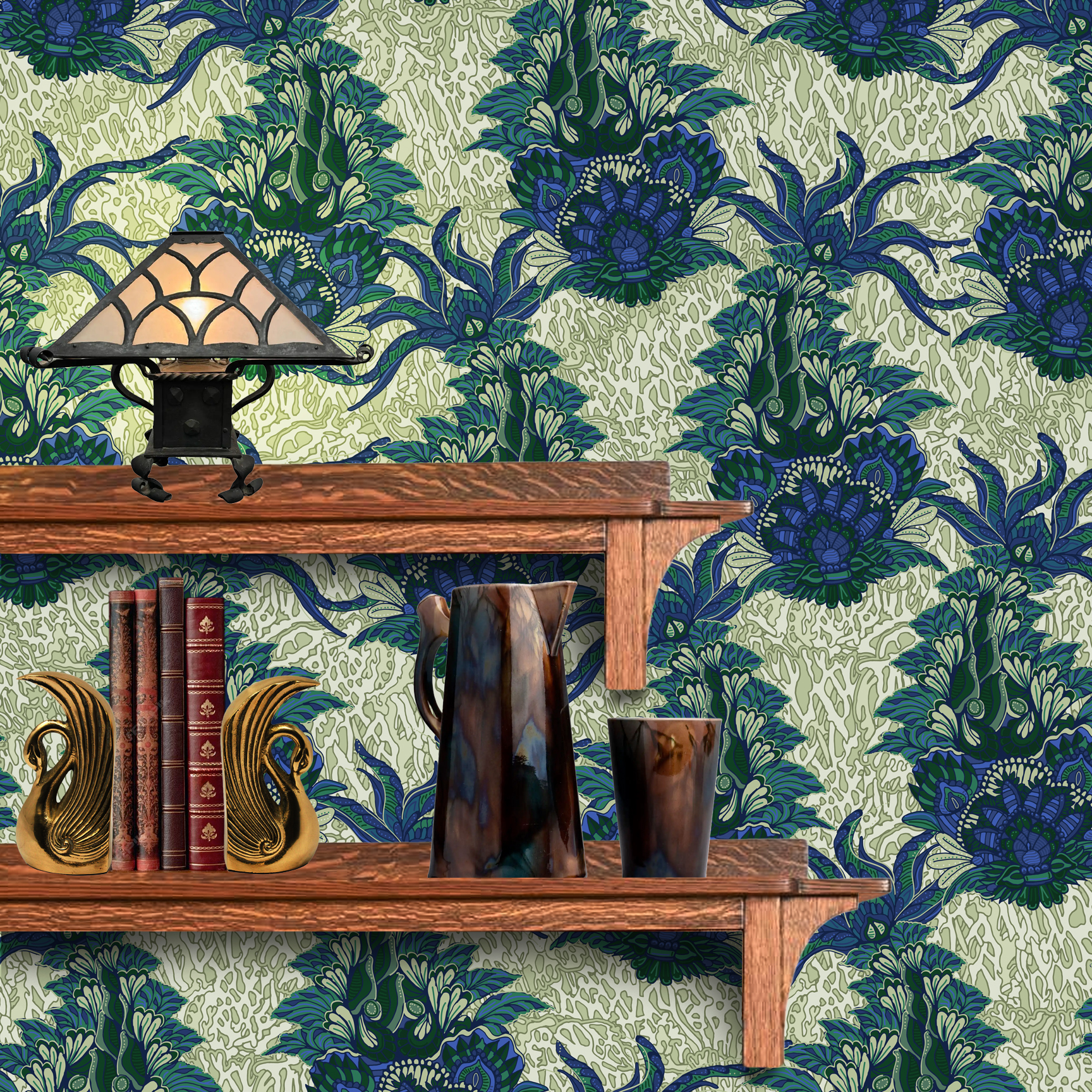 The artwork is a textile design featuring an intricate floral pattern. It showcases large, stylized flowers primarily in shades of blue and green. The flowers have detailed petals with layered, petal-like shapes creating a sense of depth and richness. Interwoven with the flowers are long, curved leaves and stems, adding dynamic movement to the composition. The background consists of a muted, light beige area patterned with subtle, organic shapes that resemble small leaves or plant forms, providing texture without overwhelming the main floral elements. The wallpaper design is shown behind a Mission style shelf.