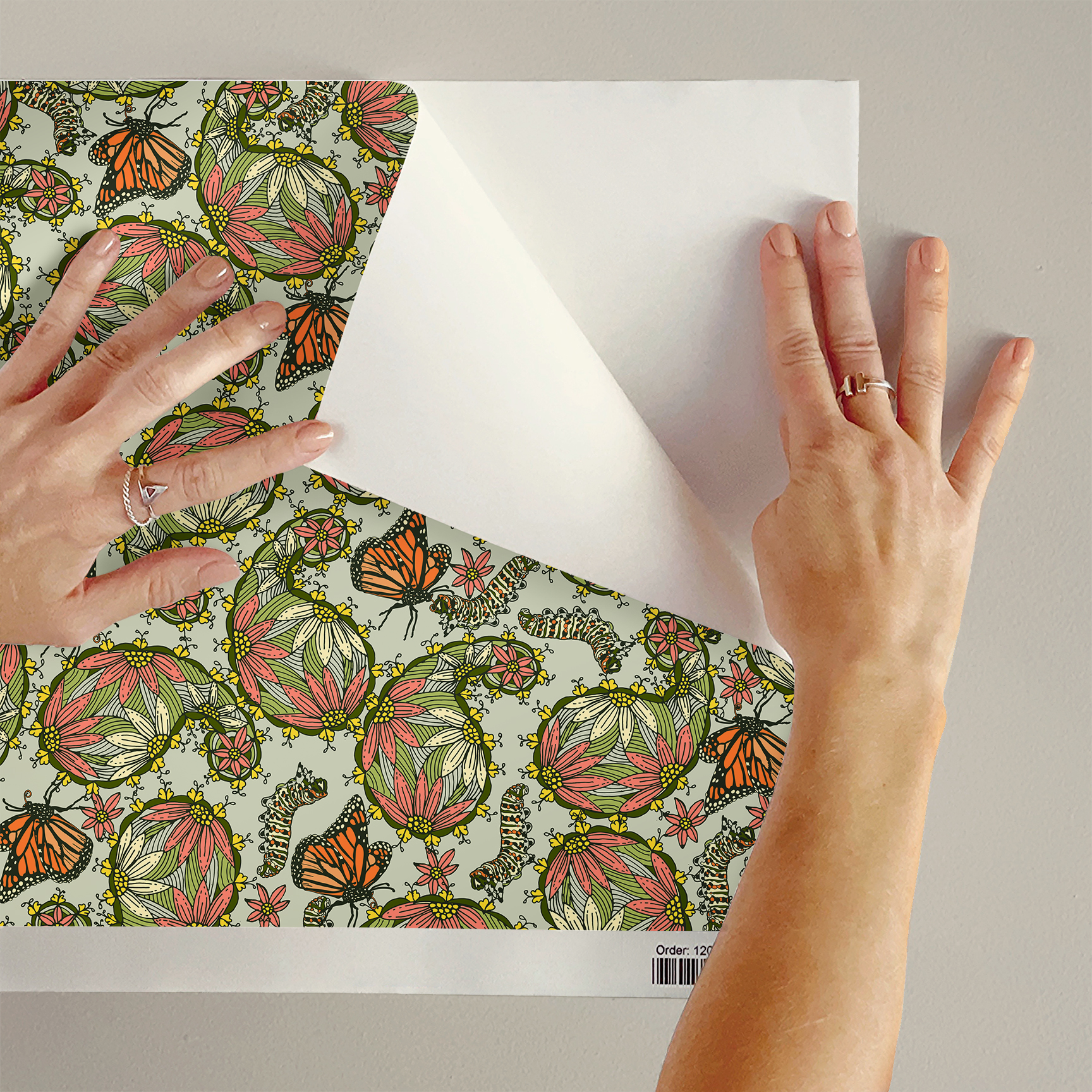 The artwork features a dense, seamless pattern composed of intricately detailed butterflies, caterpillars, and flowers. The butterflies are primarily orange with black and white accents, conveying a monarch butterfly design. The caterpillars are segmented and textured with earthy tones of green and beige, blending naturally with the floral elements. The flowers have petals colored in shades of pale pink and green, with leaves interspersed throughout the composition. The background is a light, muted yellow, which enhances the vibrant colors of the butterflies and floral motifs. The overall design is highly decorative and organic, showcasing a lyrical interplay between the stages of a butterfly's life cycle and plant life.