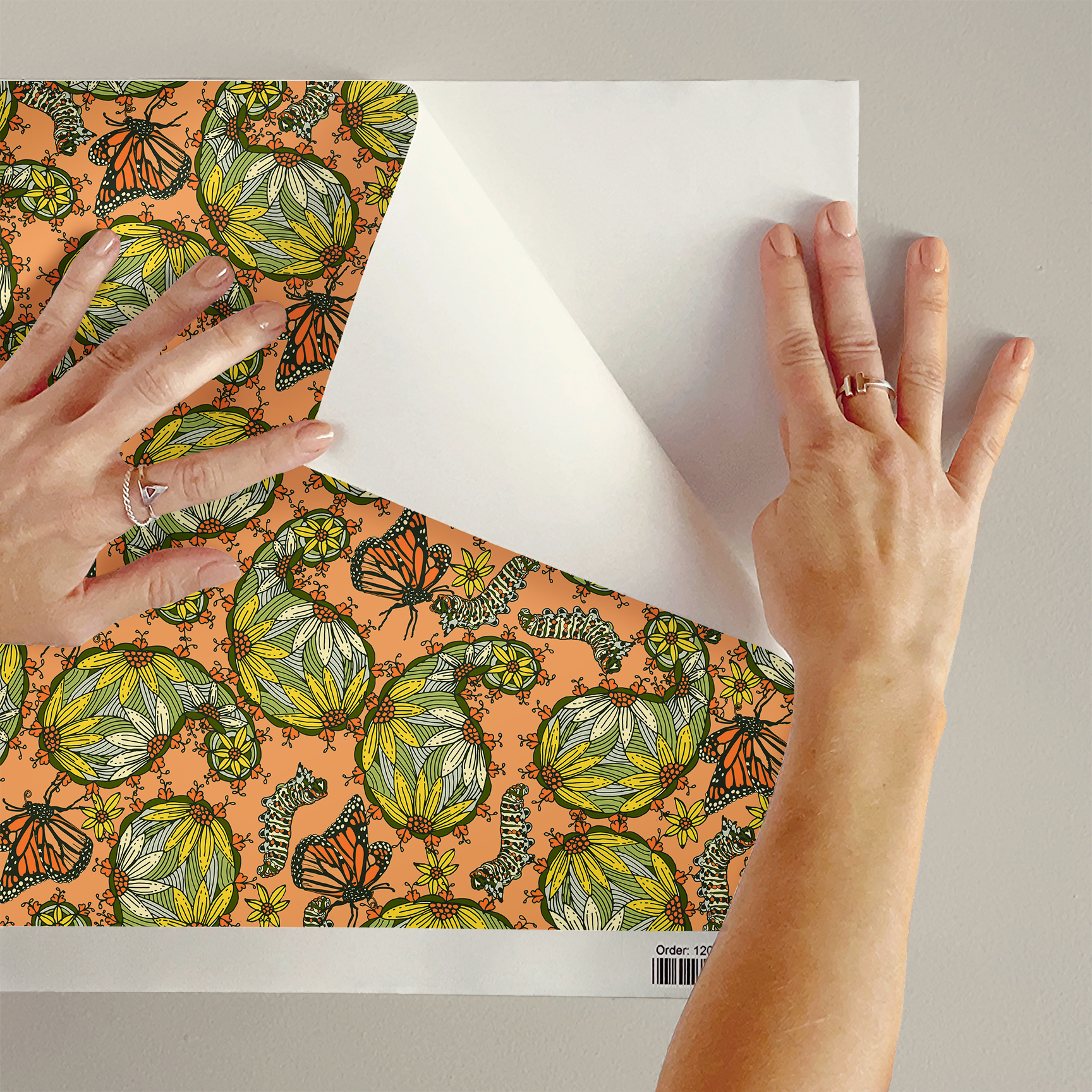 The artwork features a dense, seamless pattern composed of intricately detailed butterflies, caterpillars, and flowers. The butterflies are primarily orange with black and white accents, conveying a monarch butterfly design. The caterpillars are segmented and textured with earthy tones of green and beige, blending naturally with the floral elements. The flowers have petals colored in shades of pale pink and green, with leaves interspersed throughout the composition. The background is a light, muted yellow, which enhances the vibrant colors of the butterflies and floral motifs. The overall design is highly decorative and organic, showcasing a lyrical interplay between the stages of a butterfly's life cycle and plant life.