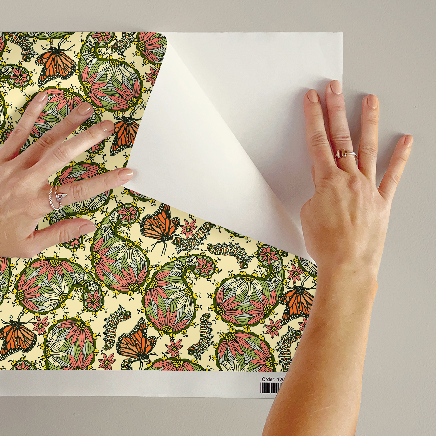 The artwork features a dense, seamless pattern composed of intricately detailed butterflies, caterpillars, and flowers. The butterflies are primarily orange with black and white accents, conveying a monarch butterfly design. The caterpillars are segmented and textured with earthy tones of green and beige, blending naturally with the floral elements. The flowers have petals colored in shades of pale pink and green, with leaves interspersed throughout the composition. The background is a light, muted yellow, which enhances the vibrant colors of the butterflies and floral motifs. The overall design is highly decorative and organic, showcasing a lyrical interplay between the stages of a butterfly's life cycle and plant life.