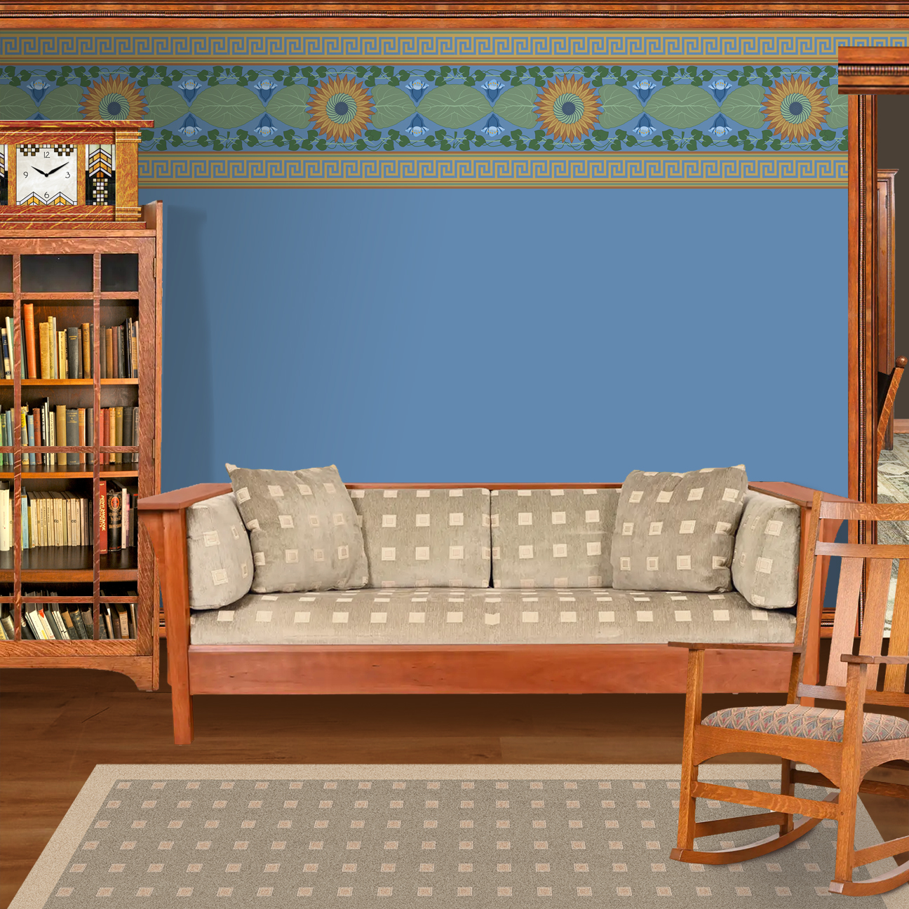 The artwork is a decorative pattern featuring a central sunflower with brown petals and a green and blue spiraled center. Surrounding the sunflower are large green leaves and a symmetric arrangement of blue flowers with rounded petals. Green vines with heart-shaped leaves intertwine around the floral elements. The design is bordered at the top and bottom by horizontal bands of Greek key motifs in gold on a blue background. The overall color palette includes shades of blue, green, brown, and gold, creating a harmonious and balanced composition.  The wallpaper design is shown in a Mission style living room