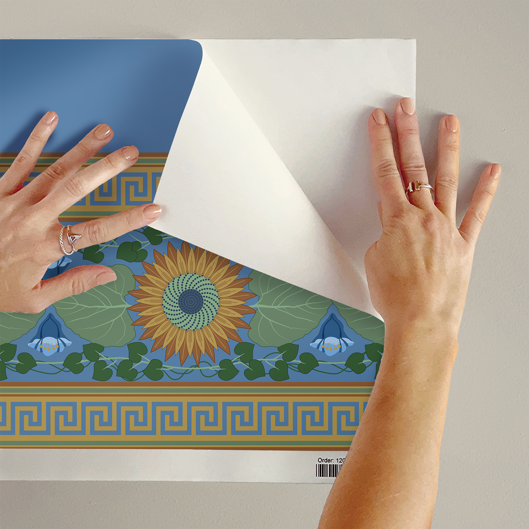 The artwork is a decorative pattern featuring a central sunflower with brown petals and a green and blue spiraled center. Surrounding the sunflower are large green leaves and a symmetric arrangement of blue flowers with rounded petals. Green vines with heart-shaped leaves intertwine around the floral elements. The design is bordered at the top and bottom by horizontal bands of Greek key motifs in gold on a blue background. The overall color palette includes shades of blue, green, brown, and gold, creating a harmonious and balanced composition.  