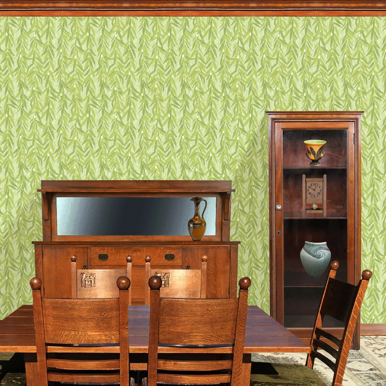 The artwork is a repeating pattern of olive branches with slender green leaves and small, light yellow-green olives set against a pale textured background. The branches hang vertically, creating a cascading effect. The color palette is composed of various shades of green and soft yellow tones, giving the piece a natural, calming, and organic feel.  The wallpaper design is shown in a Mission style dining room.